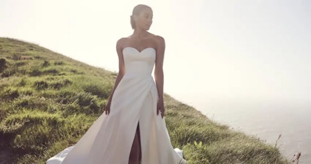 Bride wearing Zelda A-line wedding dress by Rebecca Ingram on a hillside.