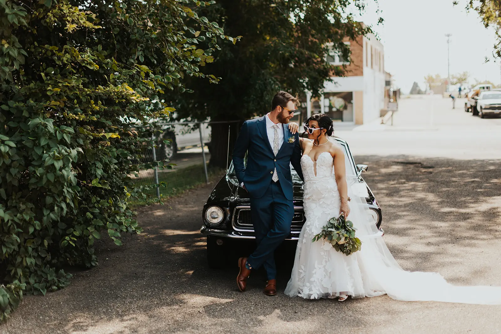 Bride wearing Hattie affordable wedding dress by Rebecca Ingram standing outside of the car with her husband.