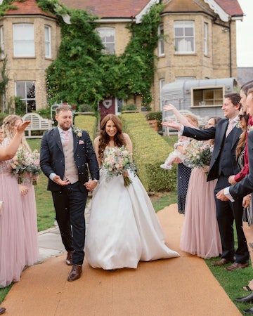 Bride wearing princess wedding dress Selena by Maggie Sottero exiting her ceremony with her husband.