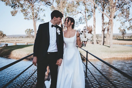 Bride wearing Selena satin wedding dress by Maggie Sottero smiling at her husband.