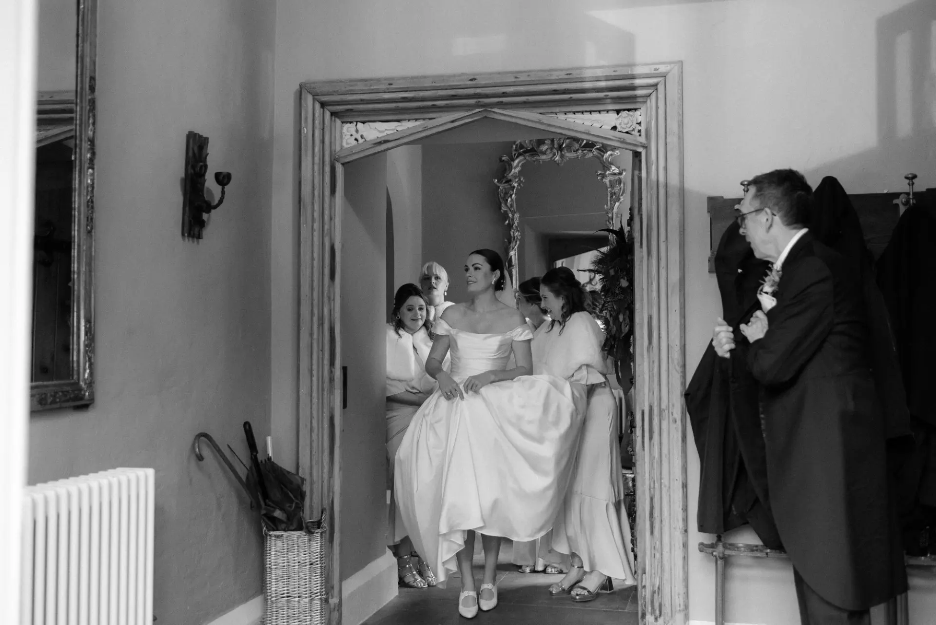 Bride wearing Scarlet simple wedding dress by Maggie Sottero surrounded by her bridesmaids getting ready.