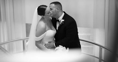 Bride wearing Anniston wedding dress with sleeves by Maggie Sottero being kissed by her husband.