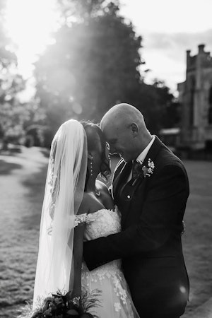 Bride wearing Harlem bridal dress by Maggie Sottero and a wedding veil embracing her husband.