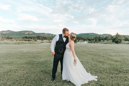 Bride wearing Minerva Western wedding dress by Rebecca Ingram kissing her husband.