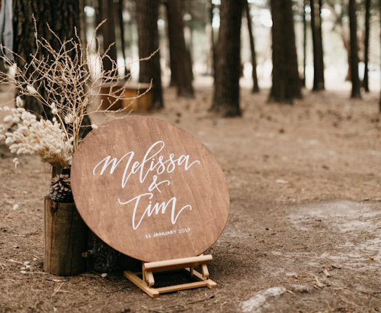 Circle wedding sign with the text "Melissa & Tim" with trees in the background