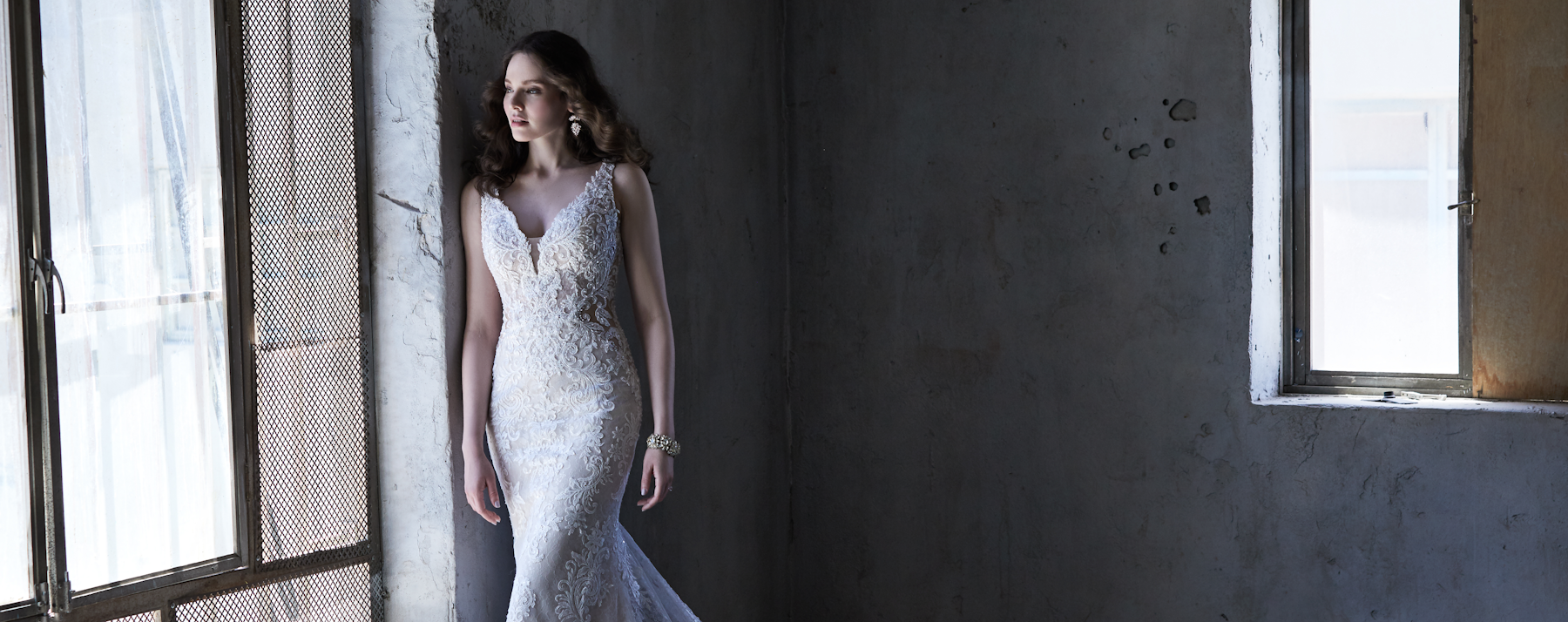 Bride wearing Delilah by Maggie Sottero leaning next to window looking out